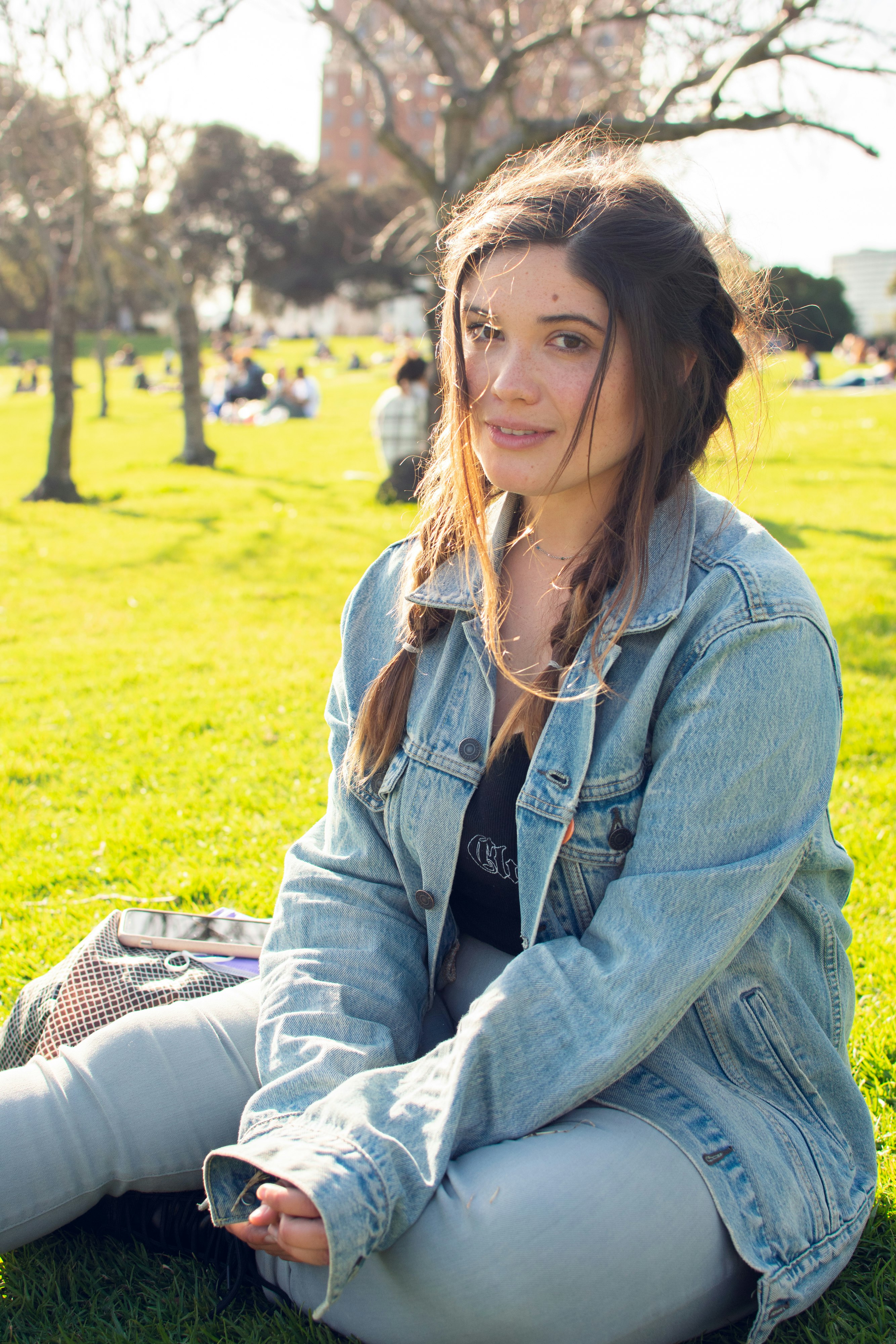 woman in blue denim jacket sitting on green grass field during daytime